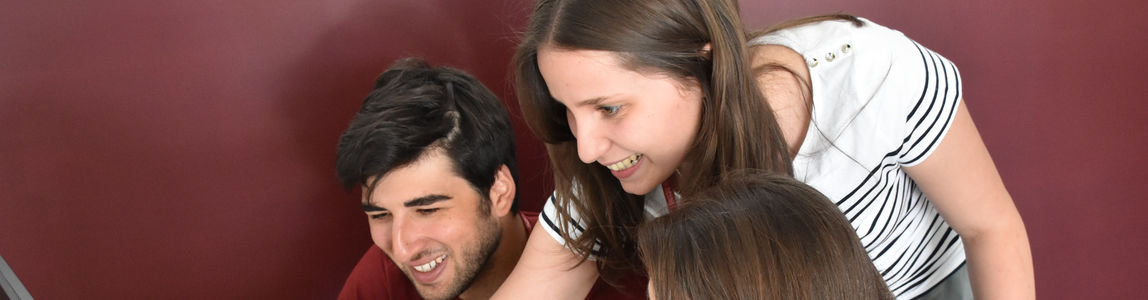 Due ragazze e un ragazzo lavorano al computer
