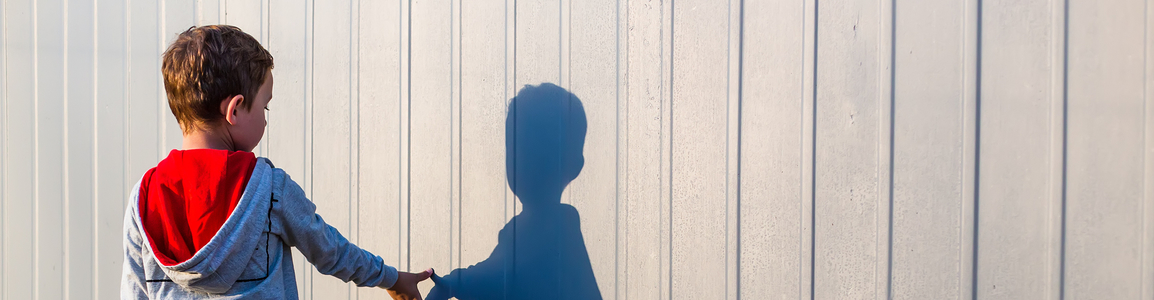 bambino davanti a un muro con la sua ombra