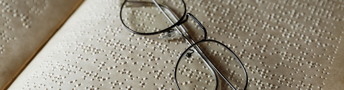 un paio di occhiali su un libro scritto in Braille
