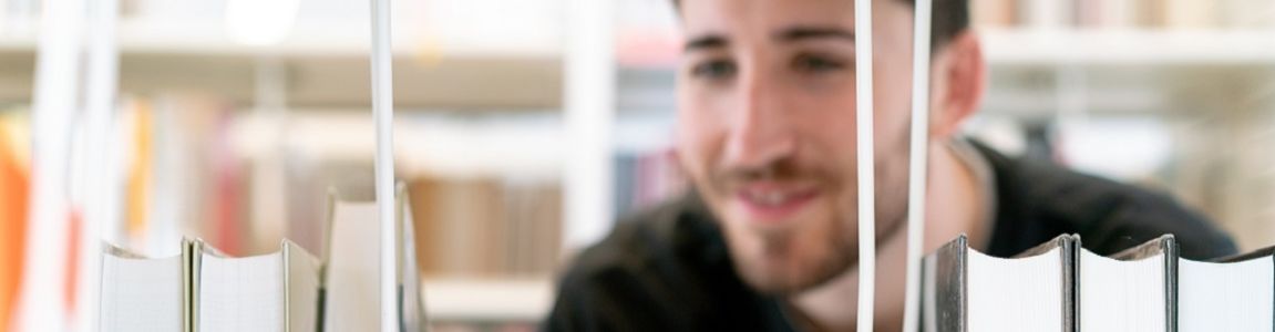 ragazzo che cerca un libro in uno scaffale 