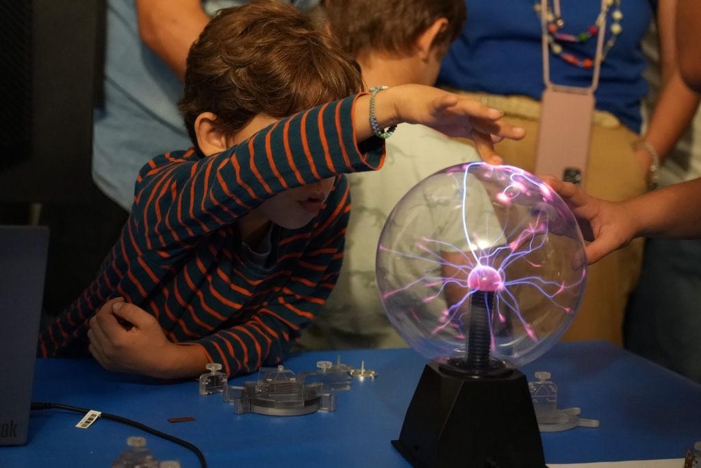 bambino che tocca una sfera con raggi elettrici