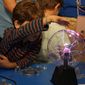 bambino che tocca una sfera con raggi elettrici